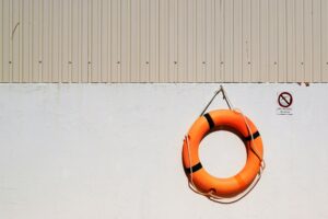 An orange flotation ring hangs on a white wall beside a No Diving sign.